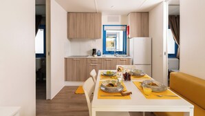 A compact kitchen with modern appliances and a dining area with a table set for breakfast. - Adria Holiday Pra' delle Torri (Caorle)
