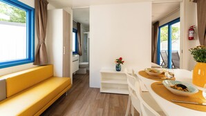 A modern kitchen with a dining area, a yellow sofa, and a view of the outside. - Adria Holiday Pra' delle Torri (Caorle)