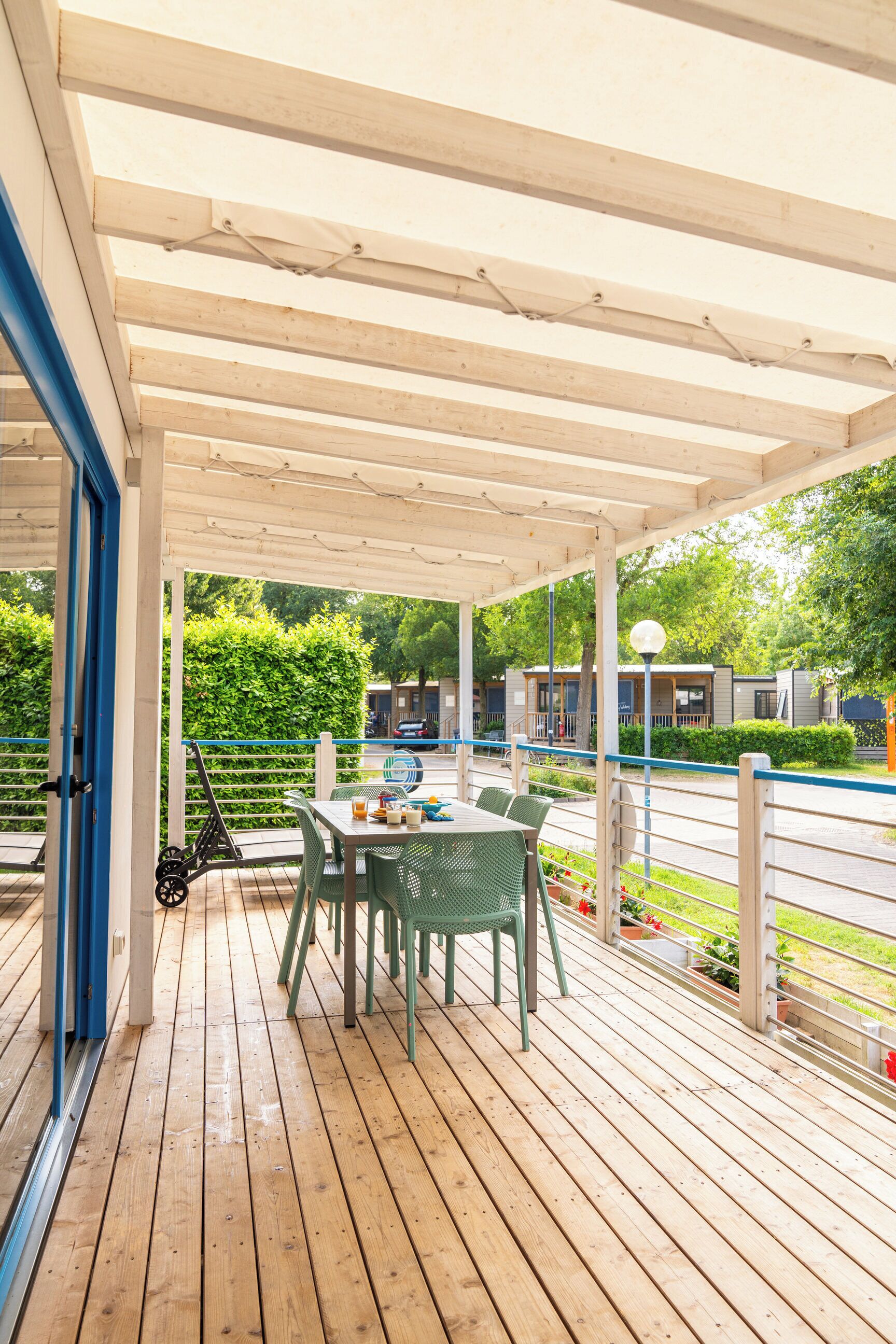 A covered outdoor area with a wooden deck, a table with chairs, and a scooter.
