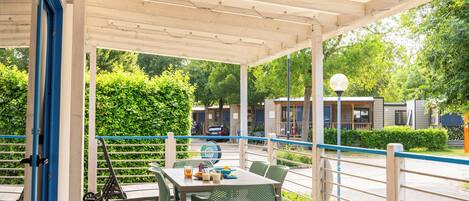 A covered outdoor area with a wooden deck, a table with chairs, and a scooter.