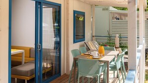 A covered outdoor area with a wooden deck, a table with chairs, and a sofa. - Adria Holiday Pra' delle Torri (Caorle)