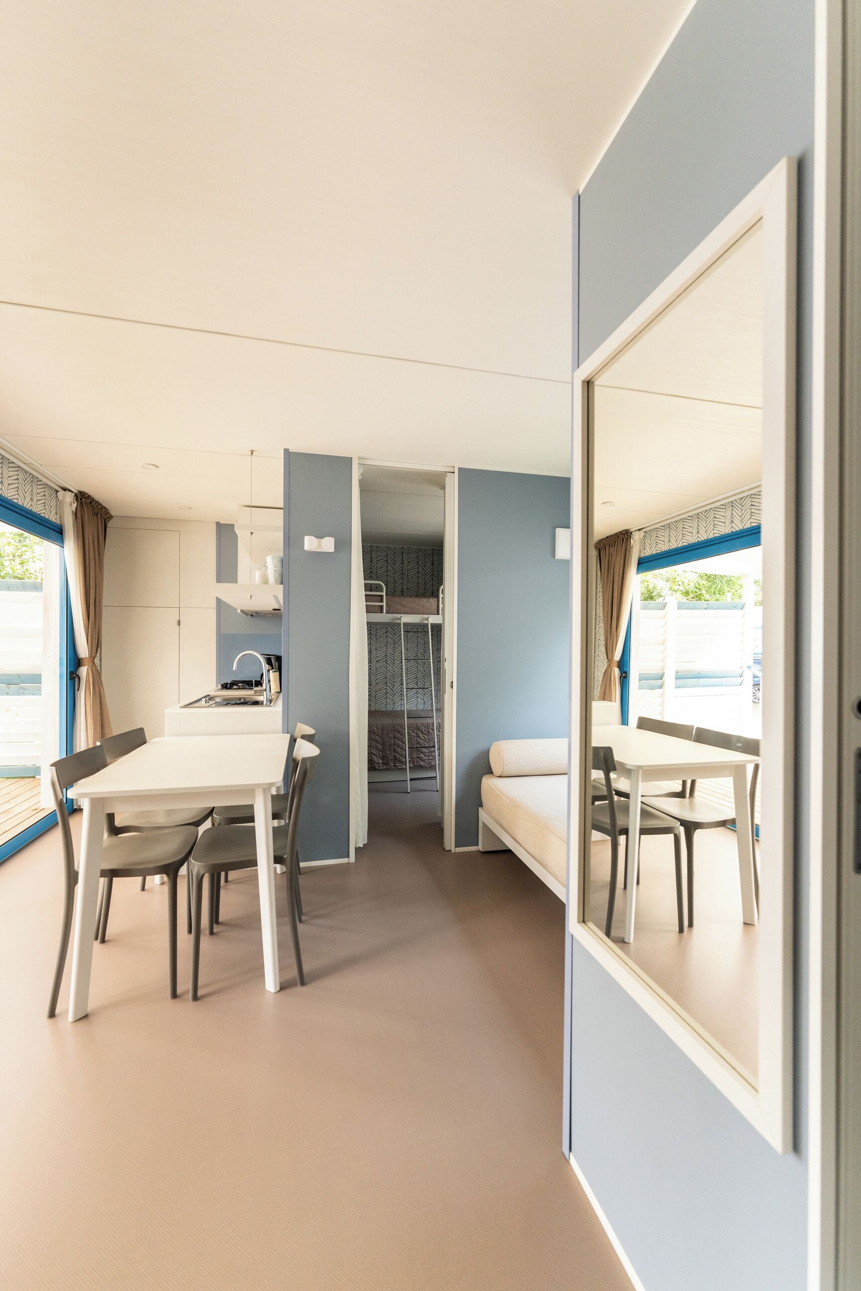 A compact room with a kitchenette, a dining area, and a bunk bed.
