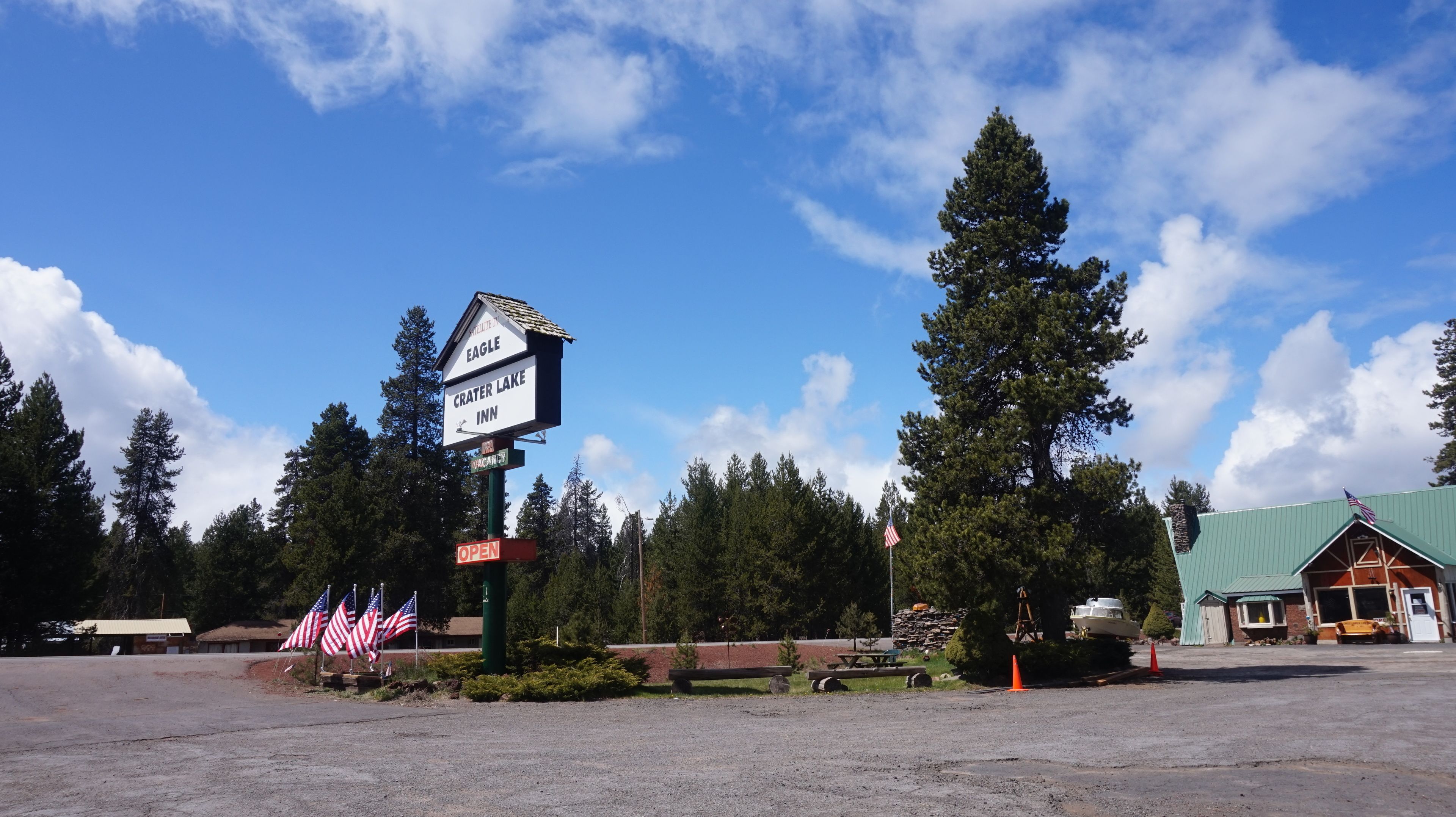 A sign for Eagle Crater Lake Inn with a clear sky and surrounding trees.