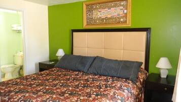 A bedroom with a patterned bedspread, a headboard, two bedside tables with lamps, and a framed picture on the wall.
