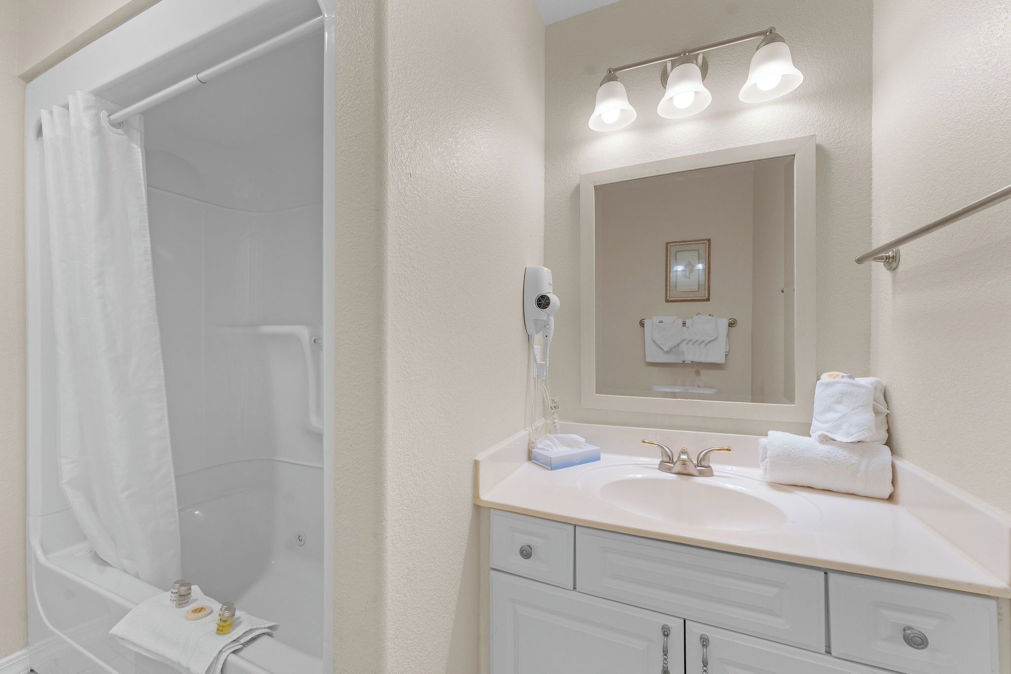 A bathroom with a bathtub, a sink, a mirror, and a towel rack.