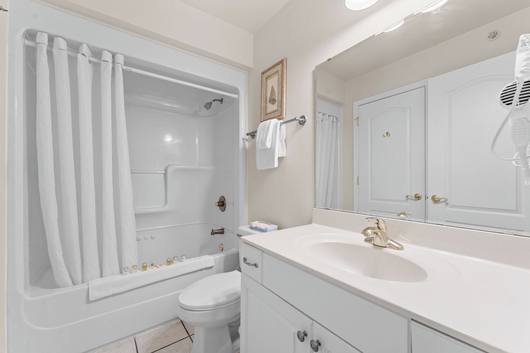 A bathroom with a bathtub, toilet, sink, and a large mirror.