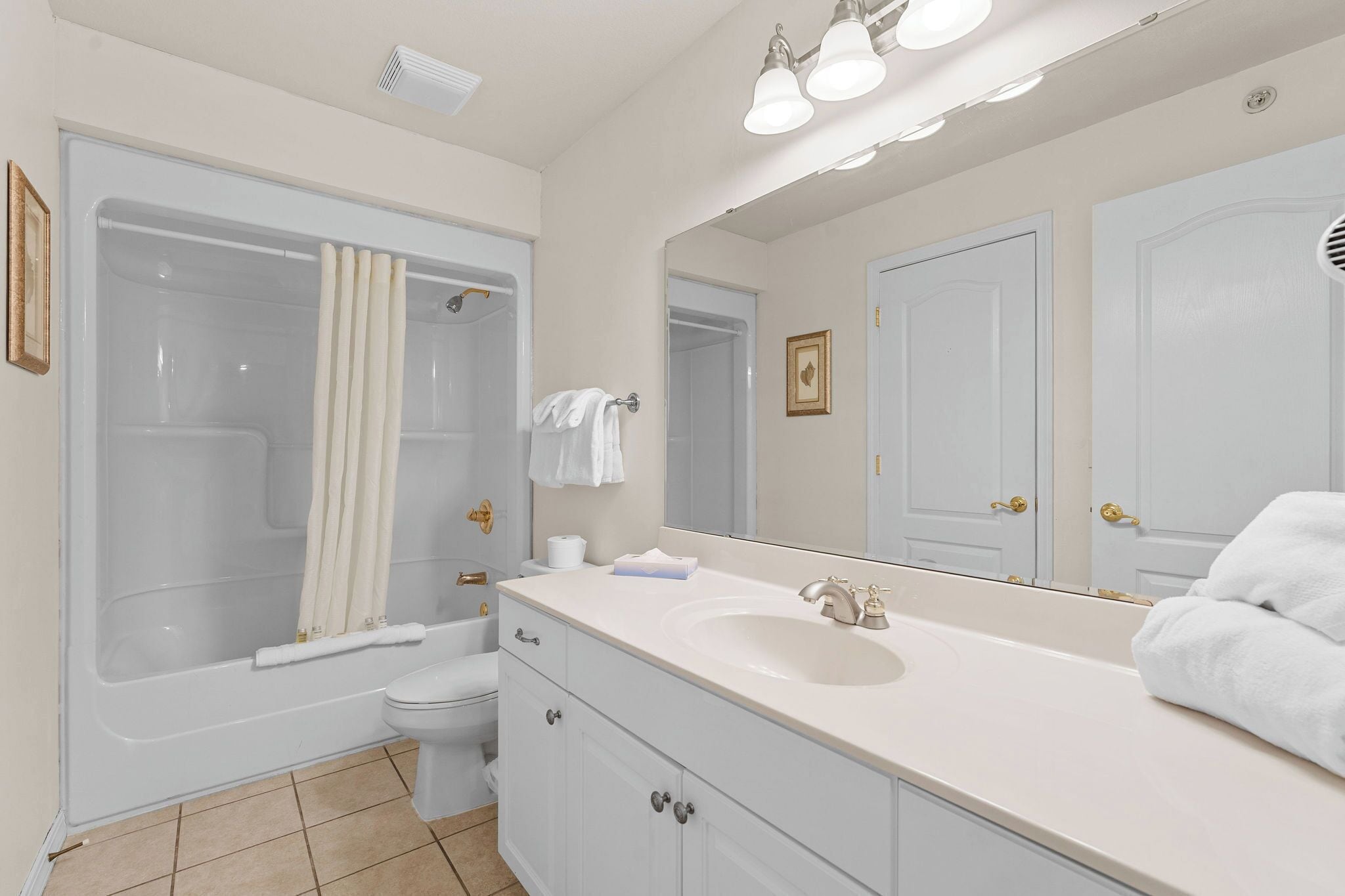 Un baño moderno con bañera, inodoro, lavabo y un espejo grande.