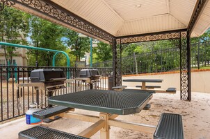 Un área de barbacoa al aire libre con parrillas y mesas de picnic.