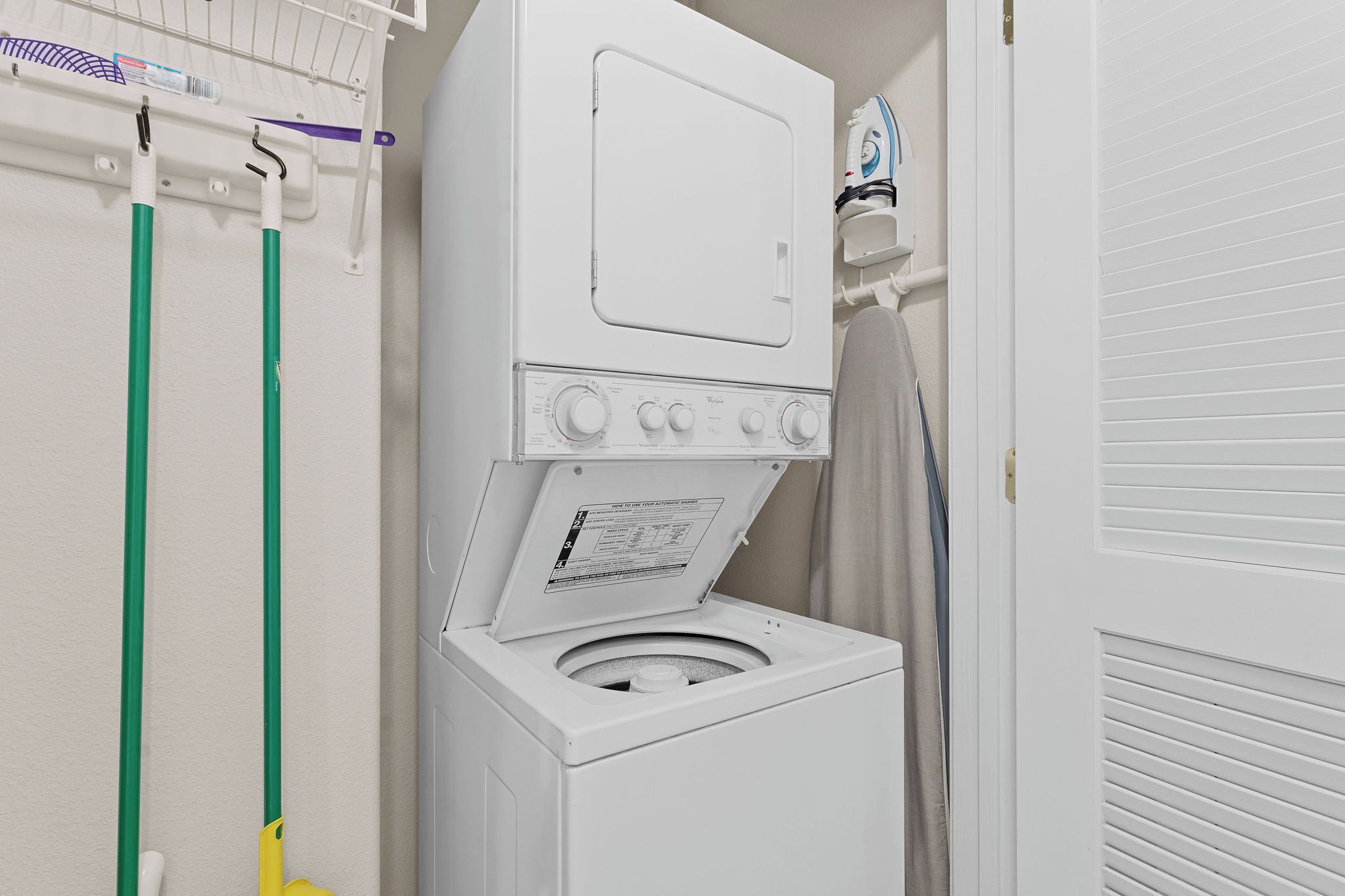 Een voorlader wasmachine met een bedieningspaneel en een ophangroede erboven.
