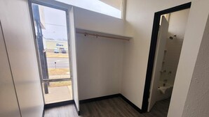 Un estrecho pasillo con suelo de madera, un perchero y una puerta que da al baño.