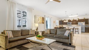 A modern living room with two sofas, a coffee table, and a kitchen in the background. - Crystal Cove by CozyKey Vacation Rentals (Kissimmee)