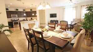 A modern kitchen with dark cabinets, a microwave, and a stove. There is a dining area with a wooden table set for four, surrounded by chairs. - Crystal Cove by CozyKey Vacation Rentals (Kissimmee)