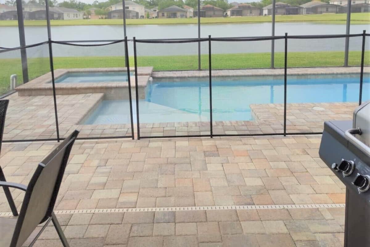 Un espace extérieur abrité comprenant une piscine, du mobilier de patio et un barbecue.