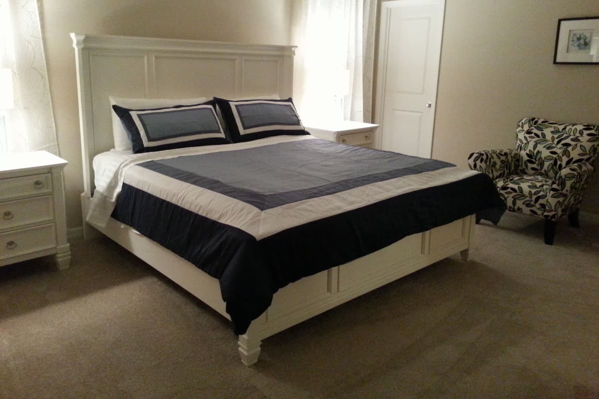 Une chambre à coucher avec un lit, des tables de chevet, une chaise et une porte.