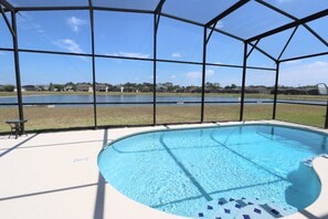 A covered swimming pool with a view of a lake and houses in the background. - Crystal Cove by CozyKey Vacation Rentals (Kissimmee)