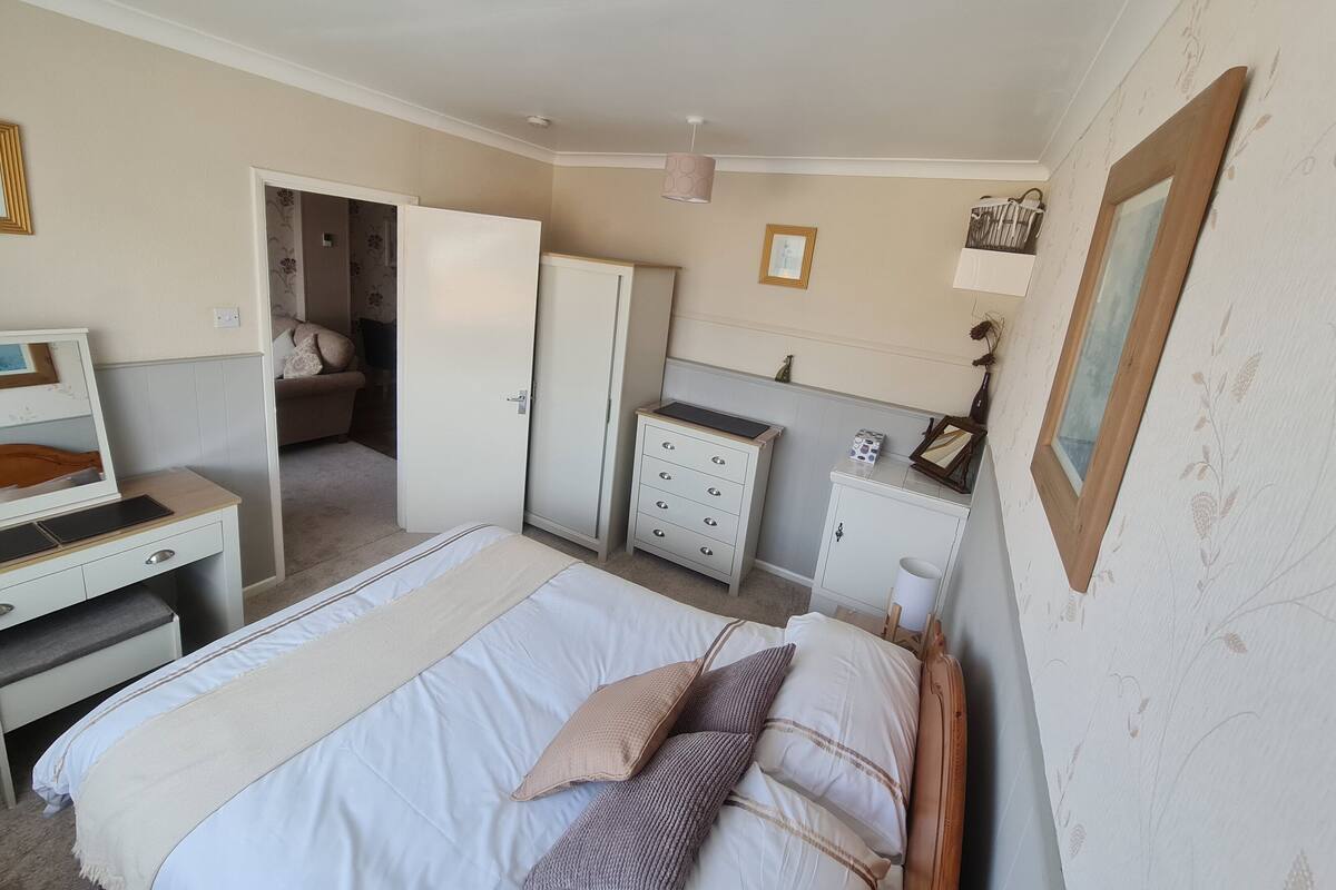 Una camera da letto con un letto, una scrivania, un armadio e una porta che dà su un'altra stanza.