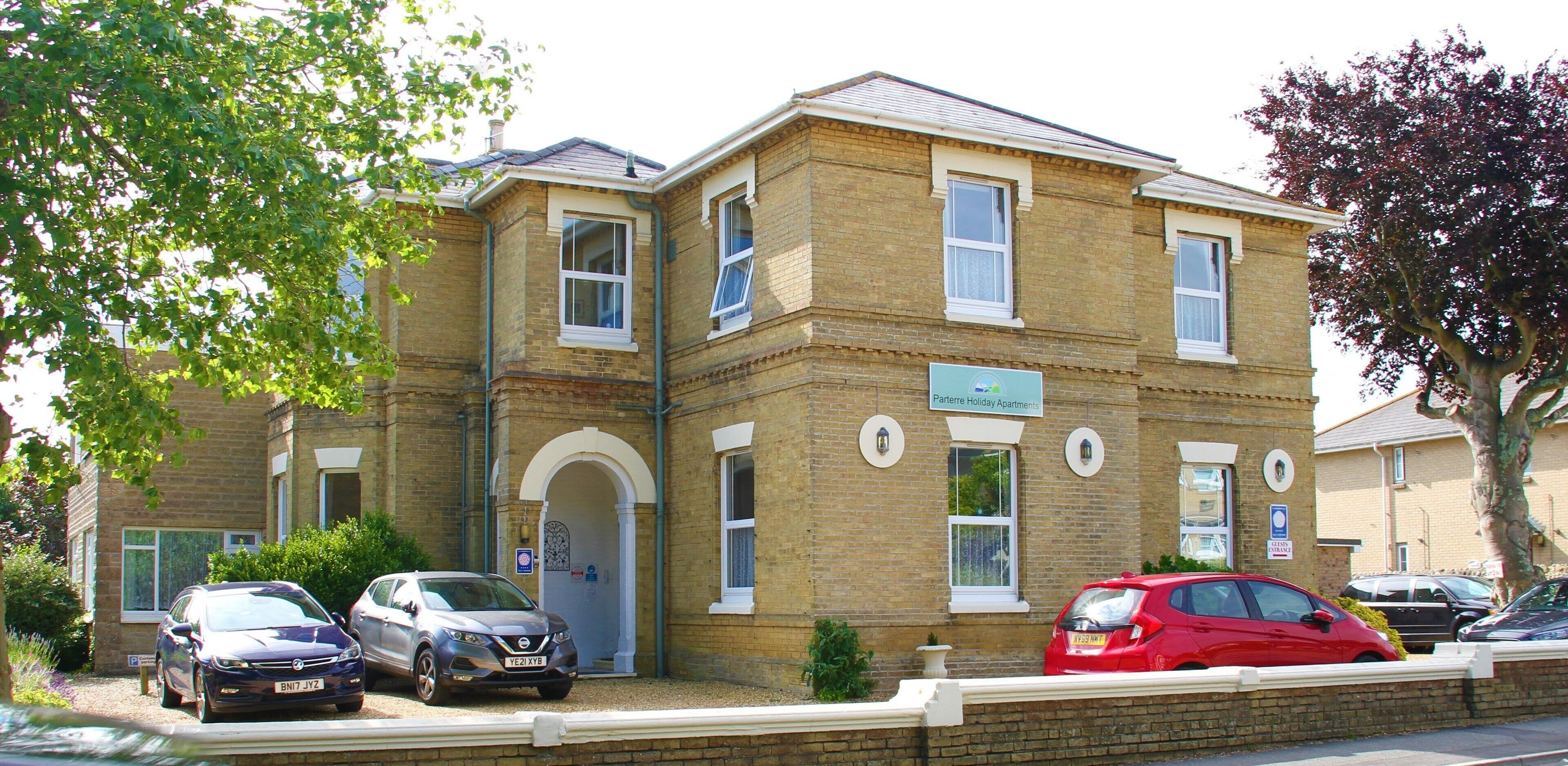 A two-story building with a brick facade, multiple windows, and a sign indicating it is a holiday apartment.