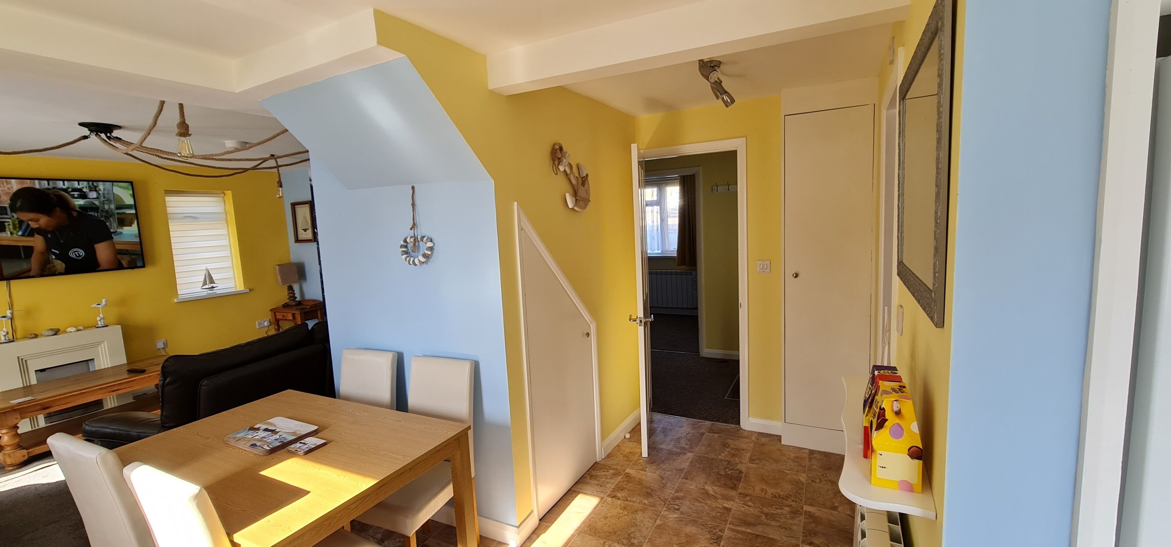 Un comedor con mesa y sillas de madera, televisor y chimenea.