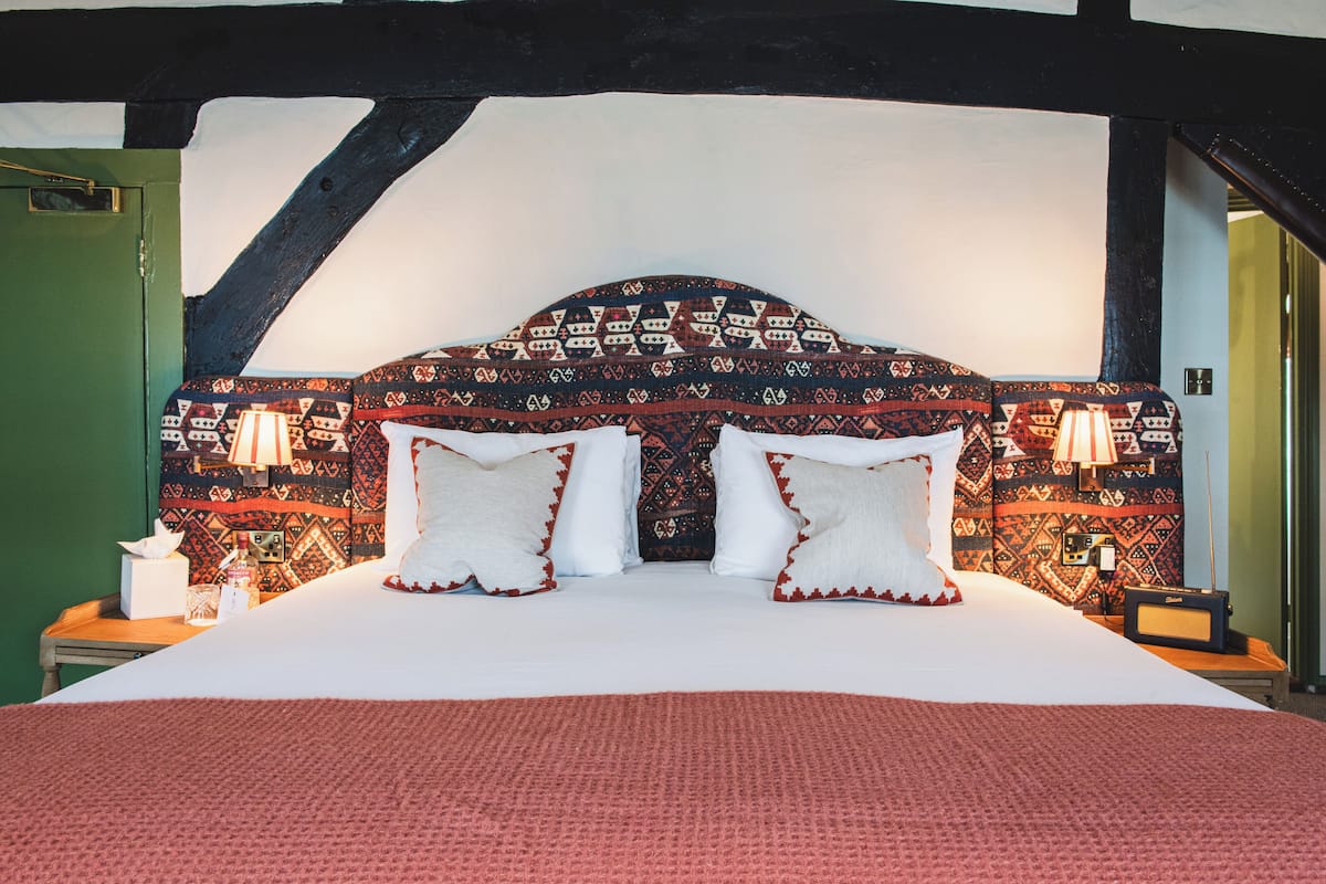 Una habitación de hotel con una cama grande, dos lámparas de noche y un cabecero estampado.