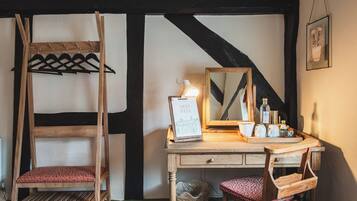 A room with a wooden desk, a hanging coat rack, a mirror, and a small basket.