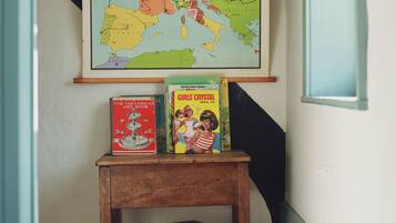 Una habitación con un mapa en la pared, una mesa de madera con libros y un taburete pequeño.
