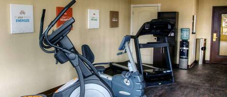 A fitness area with cardio machines, a water dispenser, and motivational posters on the wall.