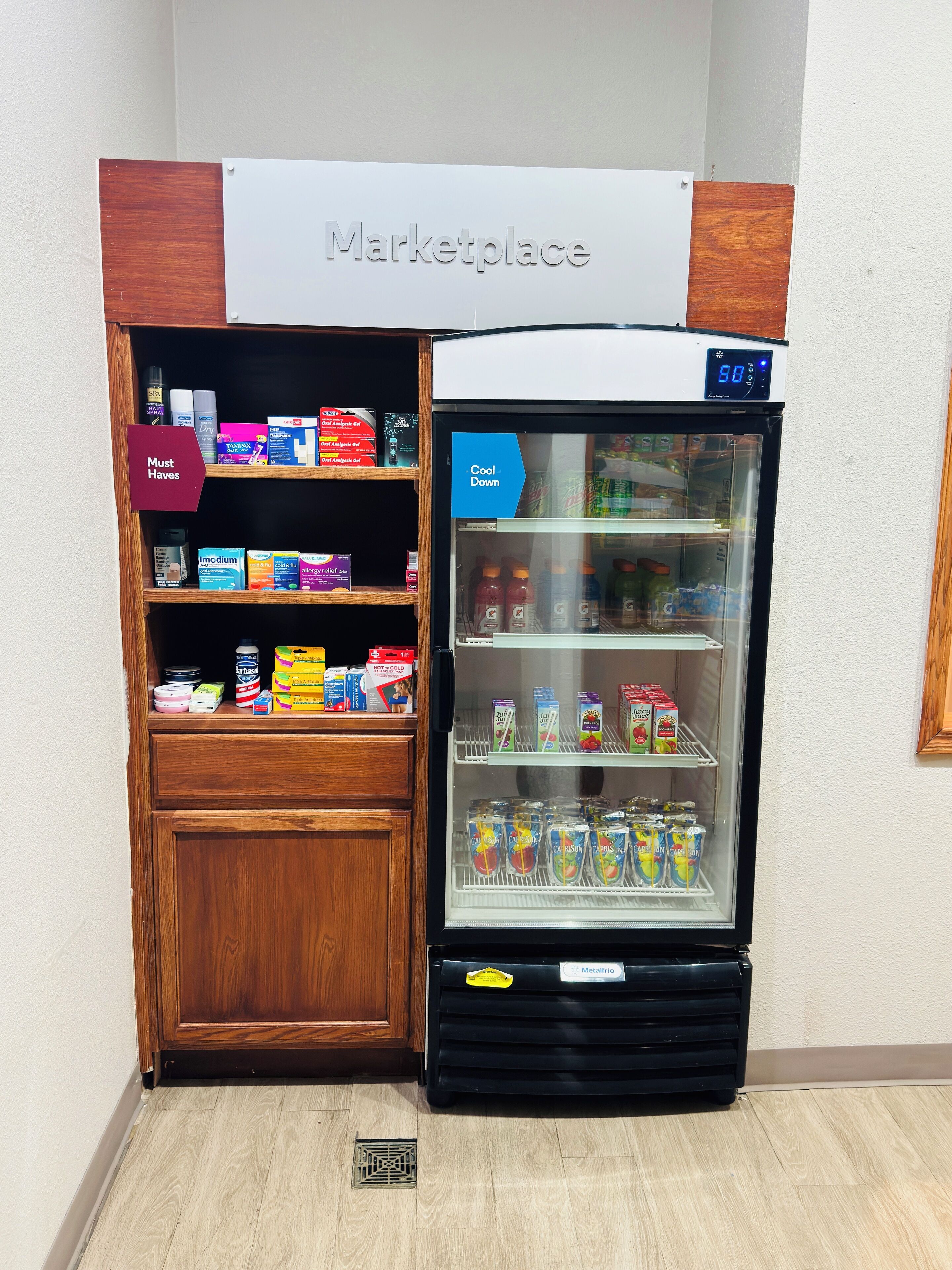 A refrigerated display case labeled "Cool Down" with various beverages and a "Must Haves" sign above it.