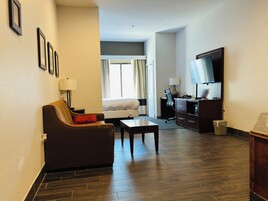 Habitación de hotel con sofá, escritorio, televisión y cama.