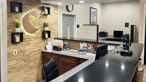 A reception area with a long counter, wooden wall paneling, a clock, and a large mirror. - Comfort Suites Plymouth near US-30 (Plymouth)