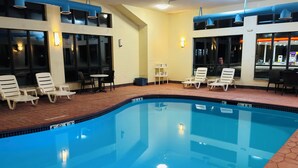 A swimming pool with lounge chairs and tables, surrounded by windows and a tiled floor. - Comfort Suites Plymouth near US-30 (Plymouth)