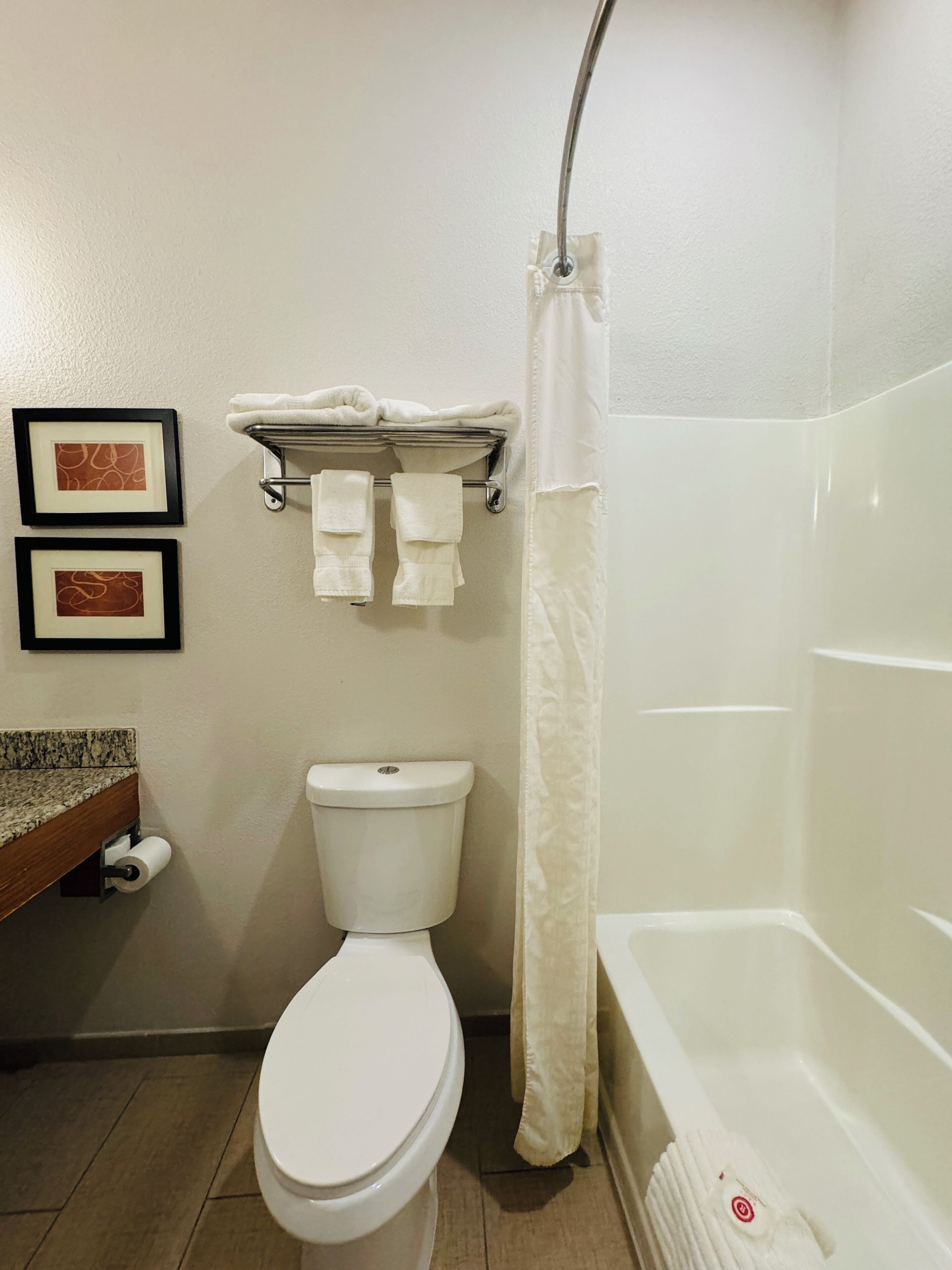 Un baño con inodoro, cortina de ducha y toallero con toallas.