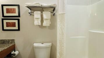 Un baño con inodoro, cortina de ducha y toallero con toallas.