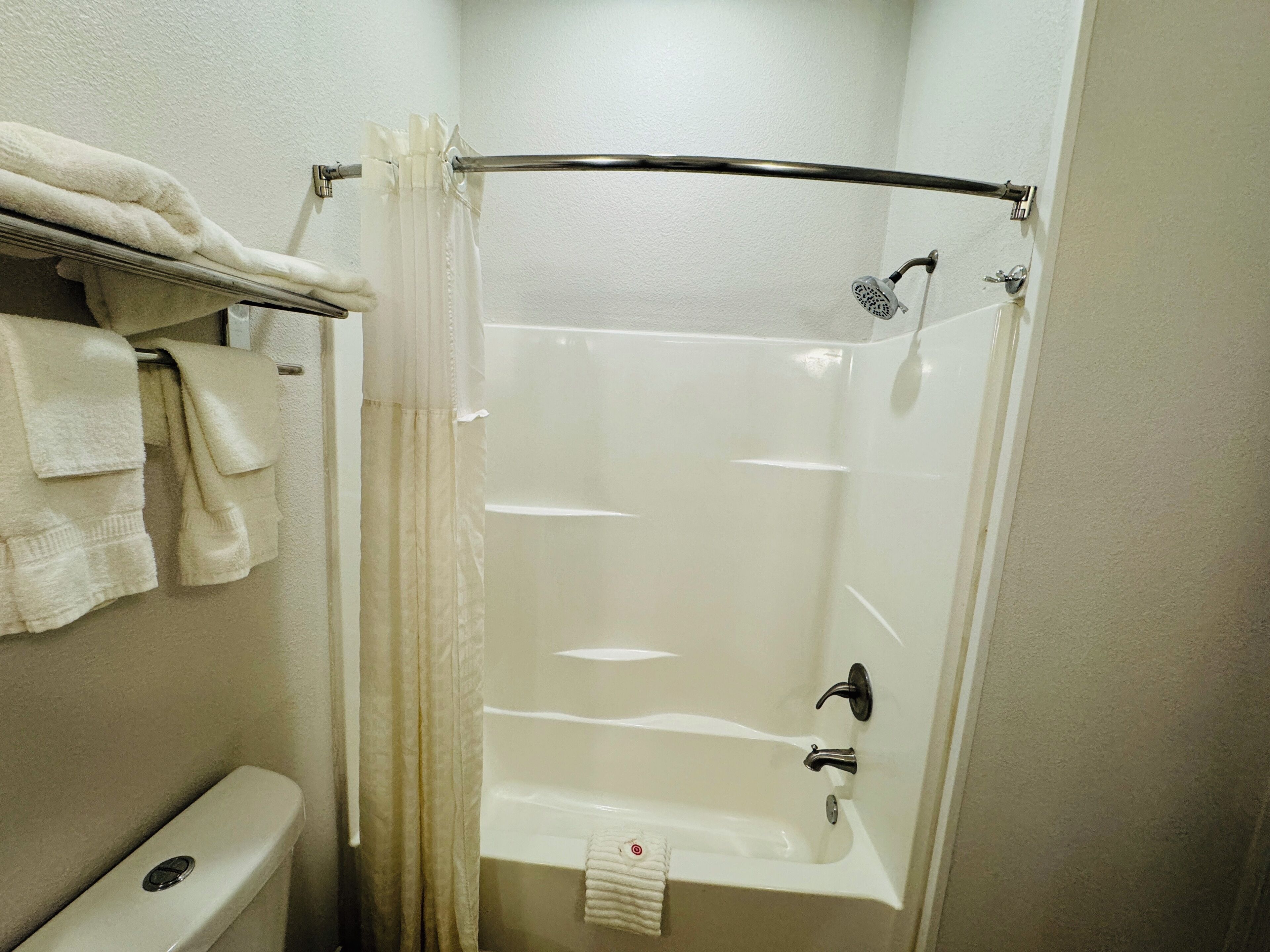 Ett litet, rent badrum med badkar, toalett och handduksställ.