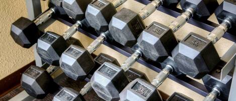A rack of hexagonal dumbbells with weight markings, arranged in rows.