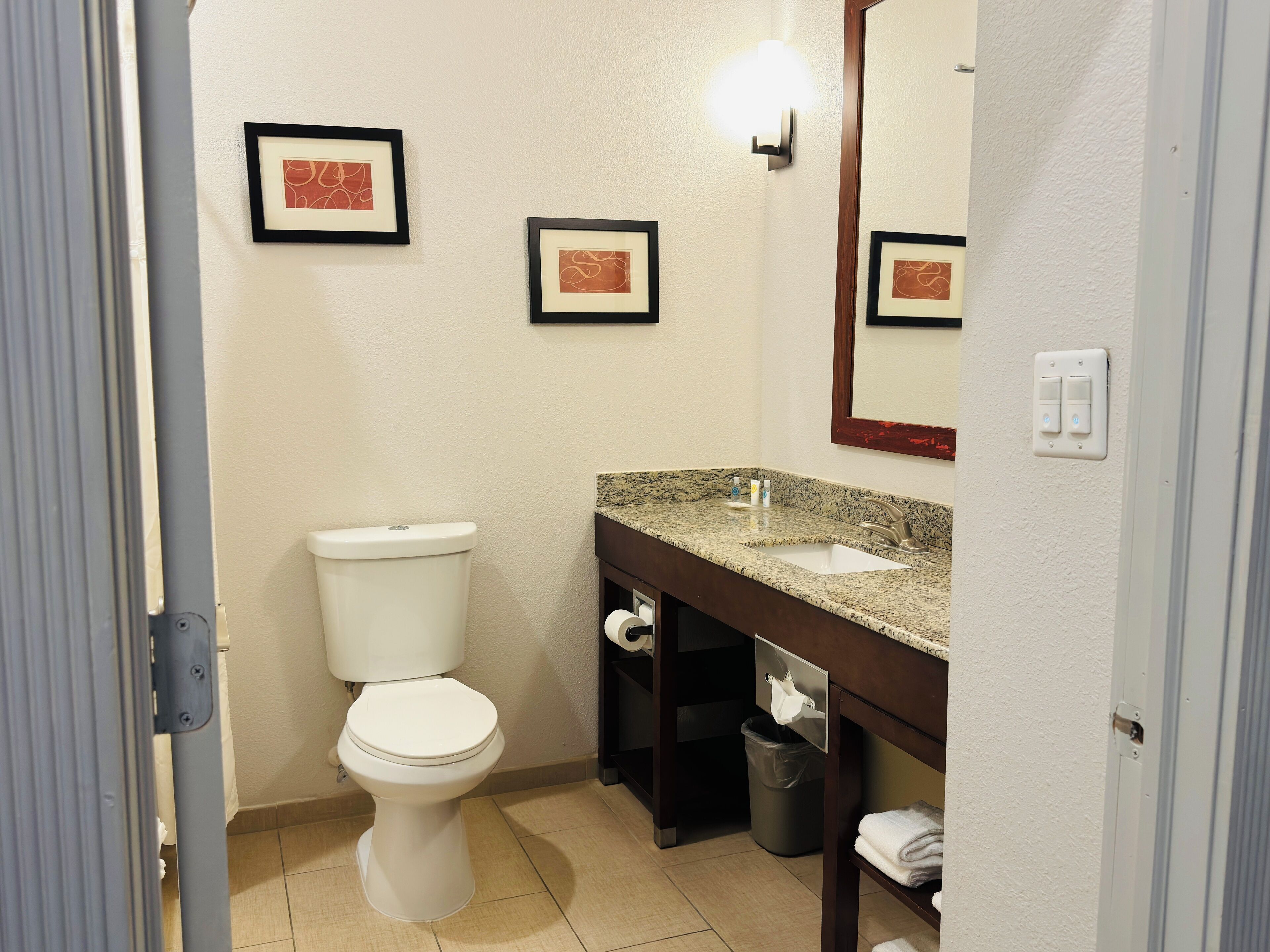 Une salle de bain d’hôtel standard, équipée de toilettes, d’un lavabo et d’une poubelle.