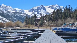 A dock with boats, a clear sky, and snow-capped mountains in the background. - Lake Front Cabins (June Lake)