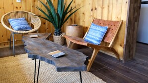 A wooden room with a rustic aesthetic, featuring a woven chair, a wooden bench, and a large potted plant. - Lake Front Cabins (June Lake)
