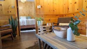 A wooden interior with a bed, a bench, a table with a plant, and a rustic decor. - Lake Front Cabins (June Lake)