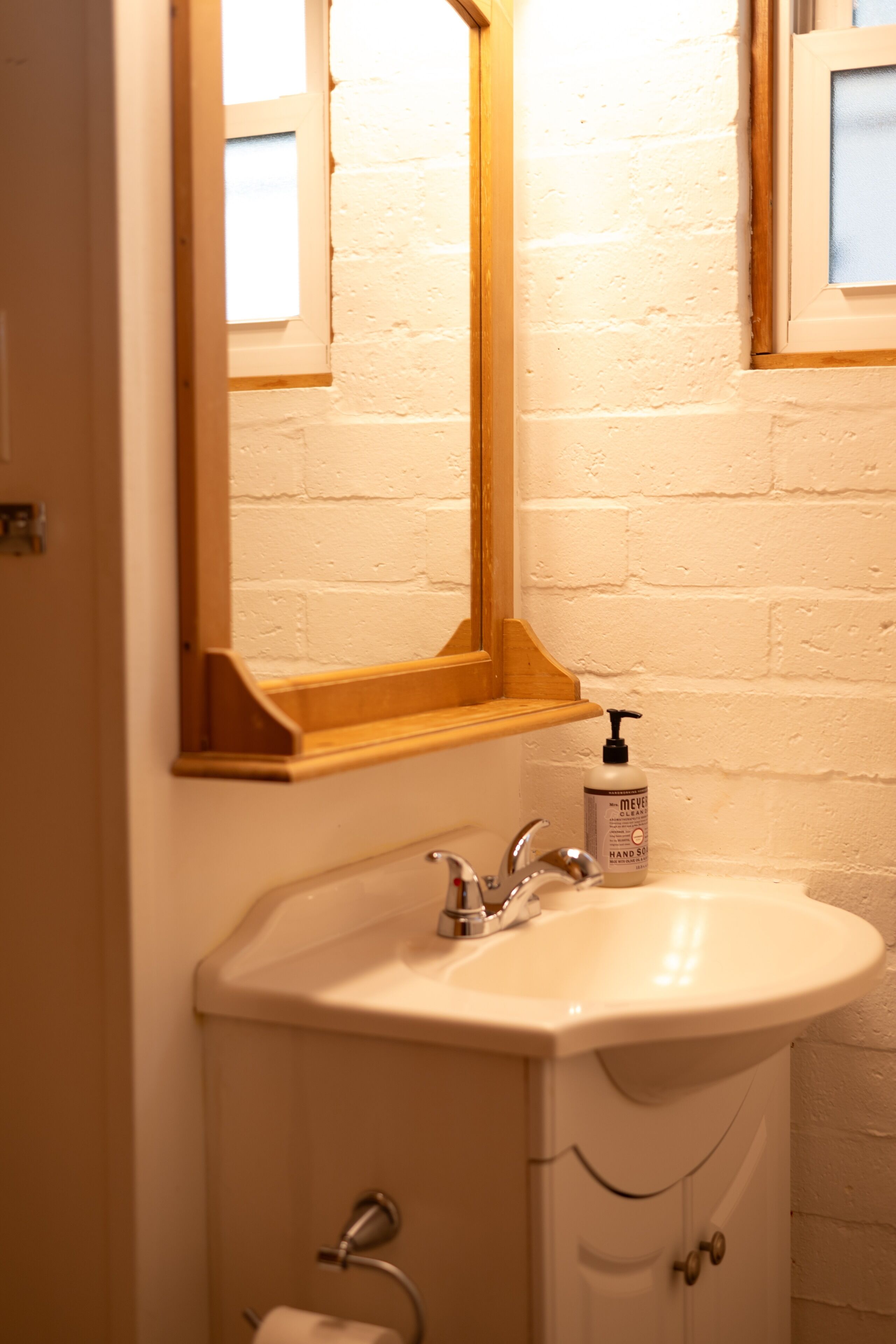 Een badkamer met een wit wastafel, een spiegel en een zeepdispenser.
