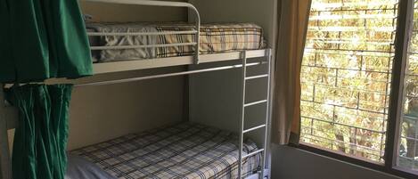 Una habitación con literas, ventana y cortinas.