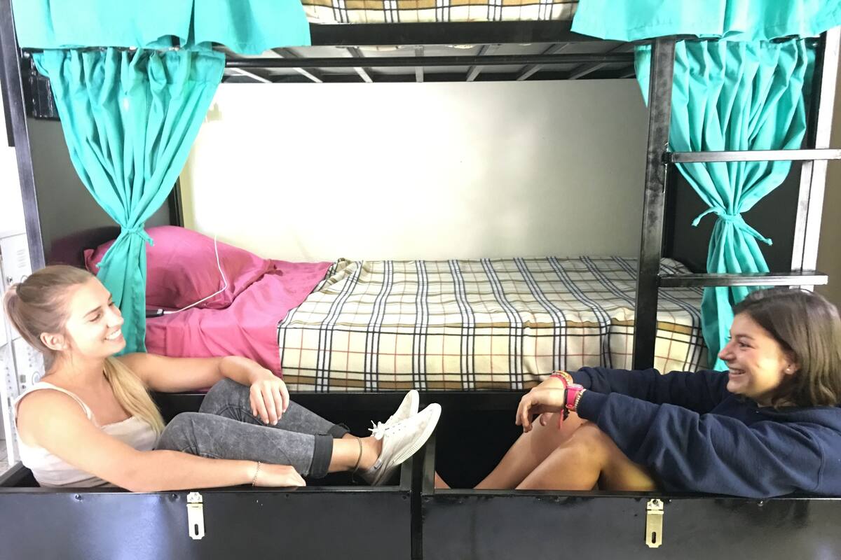 A bunk bed room with teal curtains, a plaid bedspread, and a white wall.