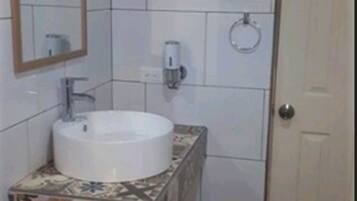 A bathroom with a white sink, a mirror, and a toilet.