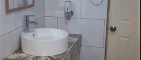 Un baño con un lavabo blanco, un espejo y un inodoro.