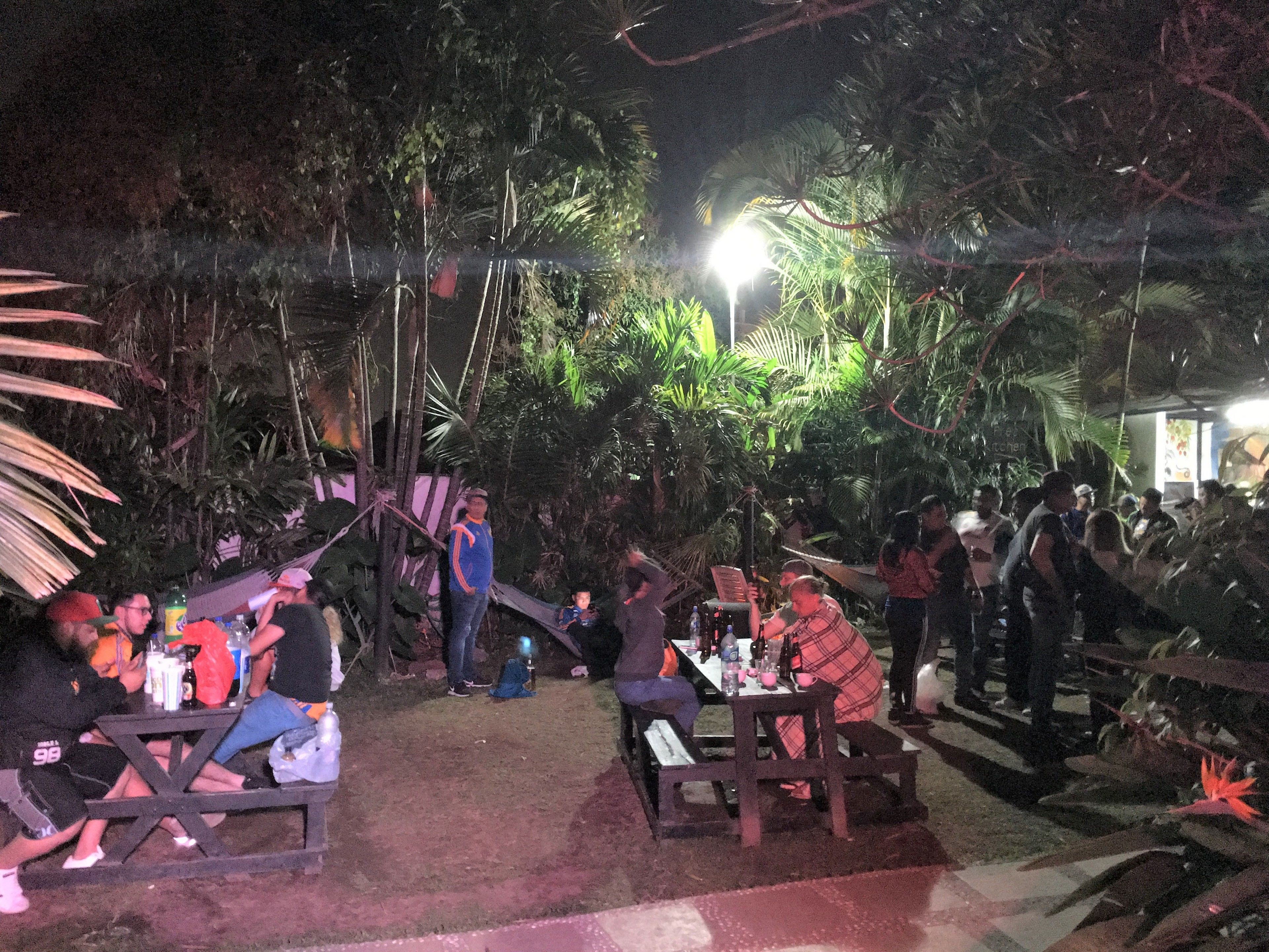 An outdoor dining area with tables and chairs, surrounded by tropical foliage.