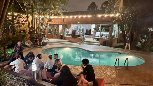 Ein Poolbereich mit Pool, Liegestühlen und einem Gebäude mit großen Fenstern.