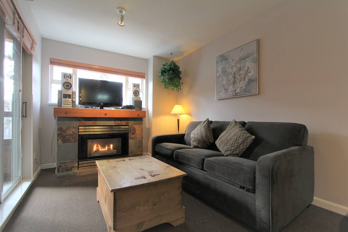 Una sala de estar con chimenea, televisor, sofá y mesa de centro.