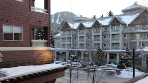 Un hotel de varios pisos con balcones, un complejo de esquí al fondo y un paisaje nevado.