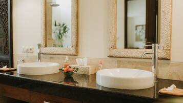 Casa de banho com duas pias, um espelho e um porta-toalhas.
