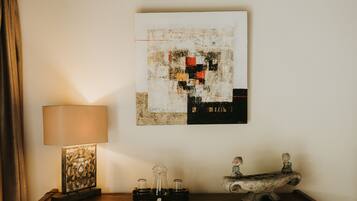 A wooden dresser with a lamp, a decorative piece, and a framed abstract artwork.