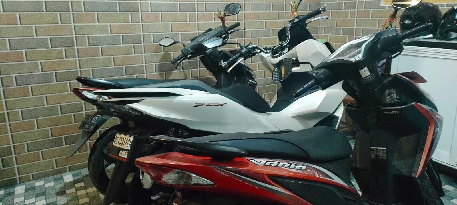 Two motorcycles parked against a brick wall.